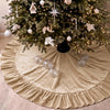 A festive velvet Christmas tree skirt with a ruffled edge surrounding a decorated evergreen tree.