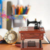 A vintage clockwork music box rests on a wooden stand next to an antique gold-rimmed clock and art supplies.