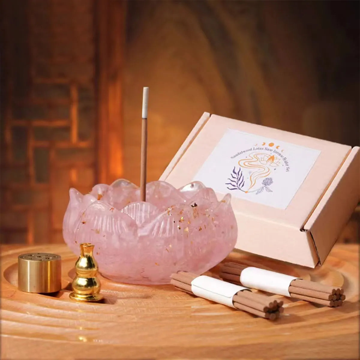 A pink crystal dropper candle set with a wooden stick and incense sticks displayed on a wooden surface.