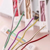 A set of six metallic twisted coil birthday candles in various colors, including green, purple, gold, and red.