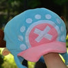 A light blue knit cap plush featuring a pink and white design with a cross motif.