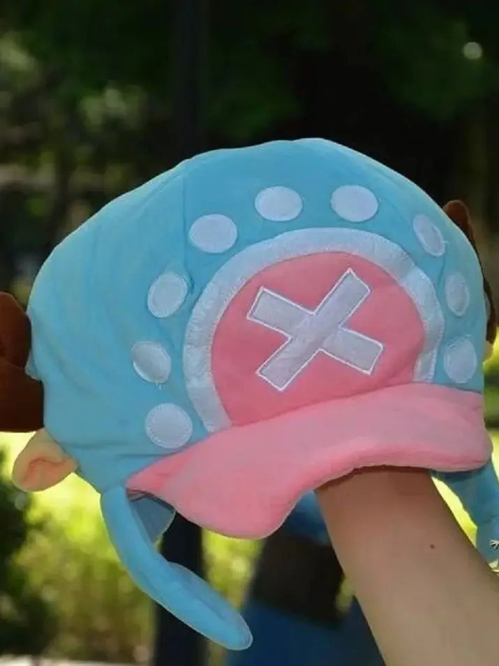 A light blue knit cap plush featuring a pink and white design with a cross motif.