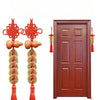 Traditional Chinese knot pendant featuring a red thread, wooden gourd, and copper coins hanging on a dark brown wooden door.