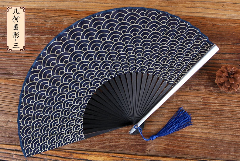 A dark blue folding hand fan with a repeating wave pattern is displayed on a wooden surface.