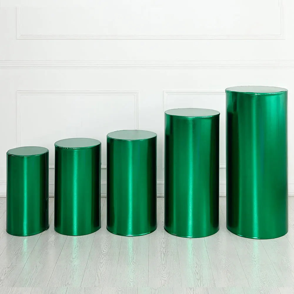 A row of six cylindrical spandex covers in a vibrant emerald green color standing on a light wooden floor.