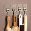 A set of five metal wall hooks with wooden and white hanging items mounted on a beige wall.
