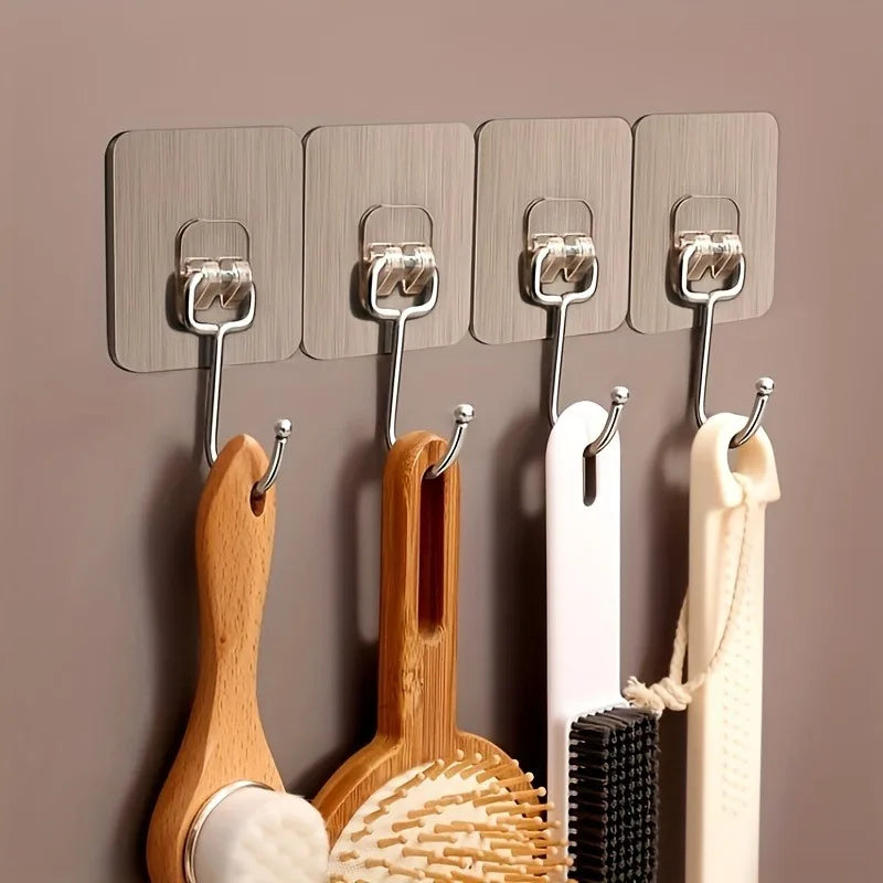 A set of five metal wall hooks with wooden and white hanging items mounted on a beige wall.