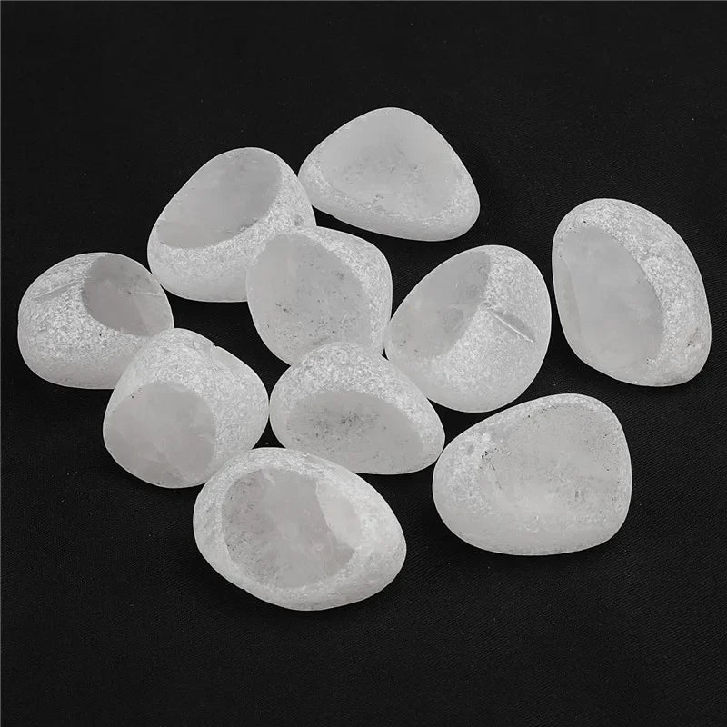 A collection of tumbled natural crystals including clear quartz, rose quartz, and amethyst in egg shapes.