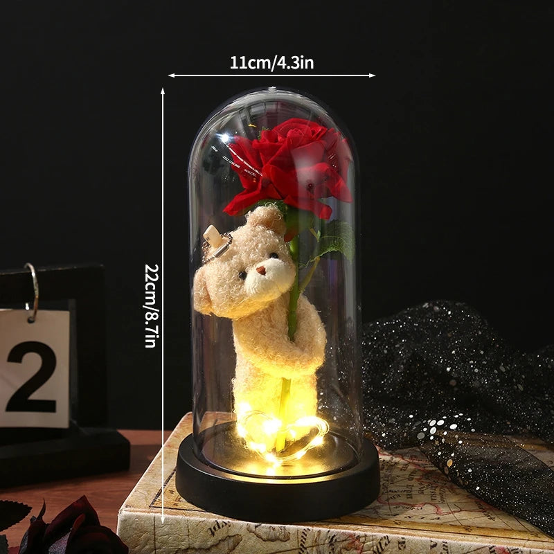 A glass dome lamp featuring a teddy bear figurine and an eternal red rose, illuminated from within.