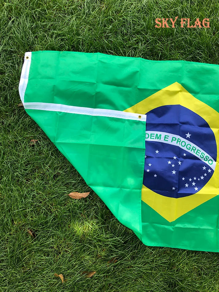 A large green and yellow Brazil flag displayed on grass.