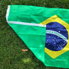 A large green and yellow Brazil flag displayed on grass.