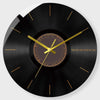 A black vinyl record style wall clock with a gold-colored face and hands.