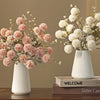 A bouquet of pink and white silk chrysanthemum artificial flowers in white vases on a wooden surface.