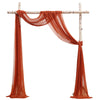 Tissu orange chiffon drapé suspendu à un cadre en bois pour un décor d'événement.