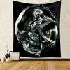 A dark tapestry wall hanging depicting a metallic alien predator head with glowing eyes and intricate armor.