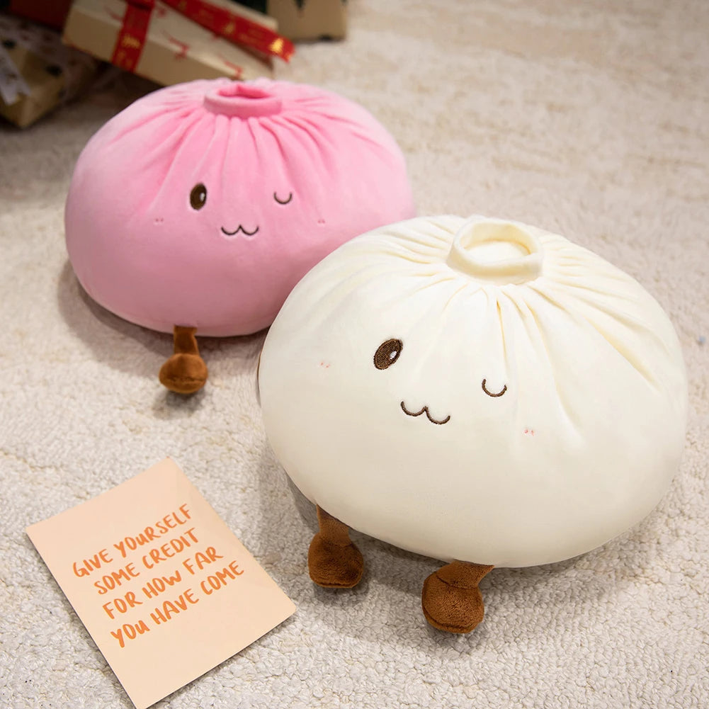 Two pink and white dumpling plush pillows with cute faces resting on a light textured surface.