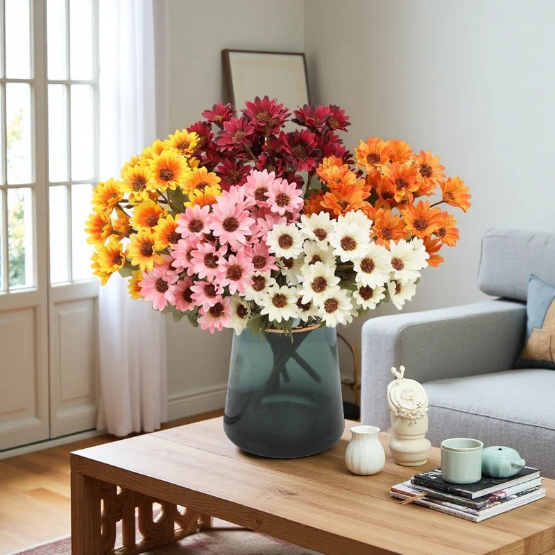A vibrant bouquet of artificial silk gerbera daisies in shades of orange, pink, and yellow displayed on a wooden table.