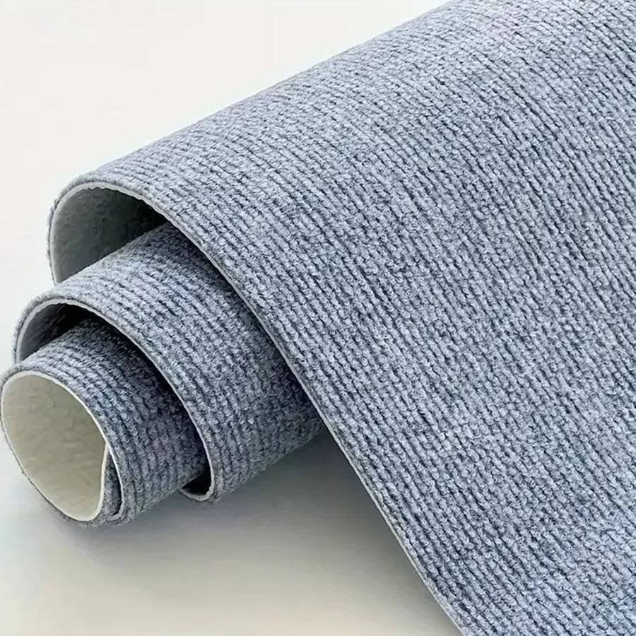 A roll of gray self-adhesive runner rug material is shown, partially unrolled.