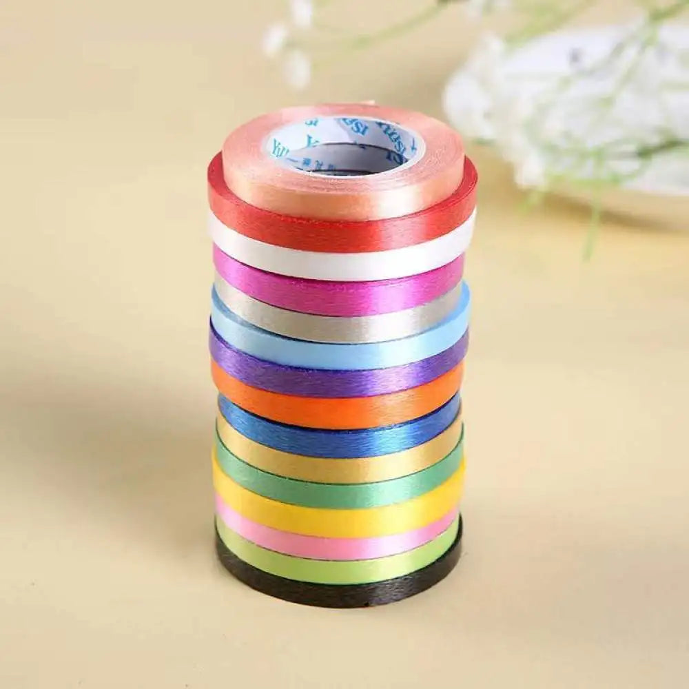A roll of satin balloon ribbon in a stack of various pastel colors like pink, blue, green, and yellow.