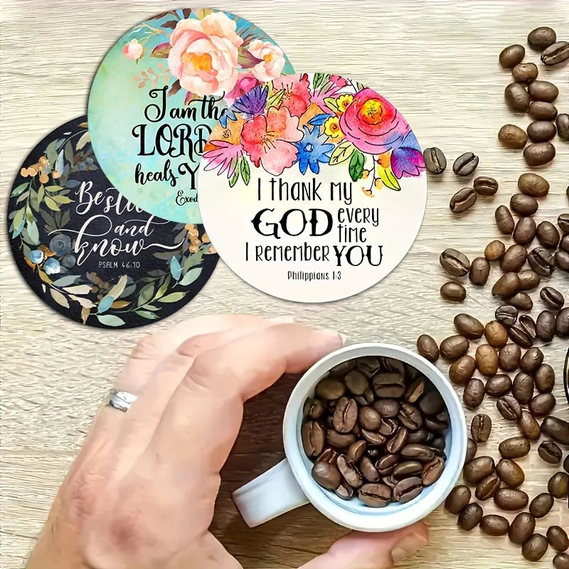 Eine Hand hält ein Set aus sechs runden Holz-Gottesdienst-Untersetzern mit floralen Designs und Bibelversen auf einer hellen 