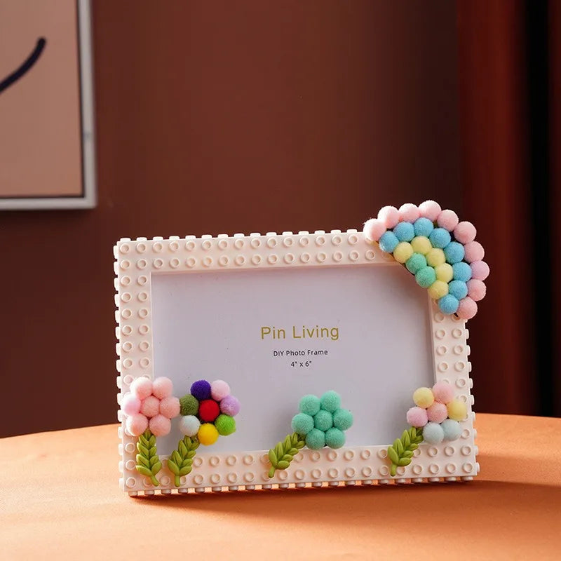 A white photo frame decorated with colorful fabric flowers and blocks, featuring the text Pin Living.