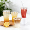 A collection of iced beverages in clear plastic cups with straws and lids, including orange, yellow, and pink drinks.