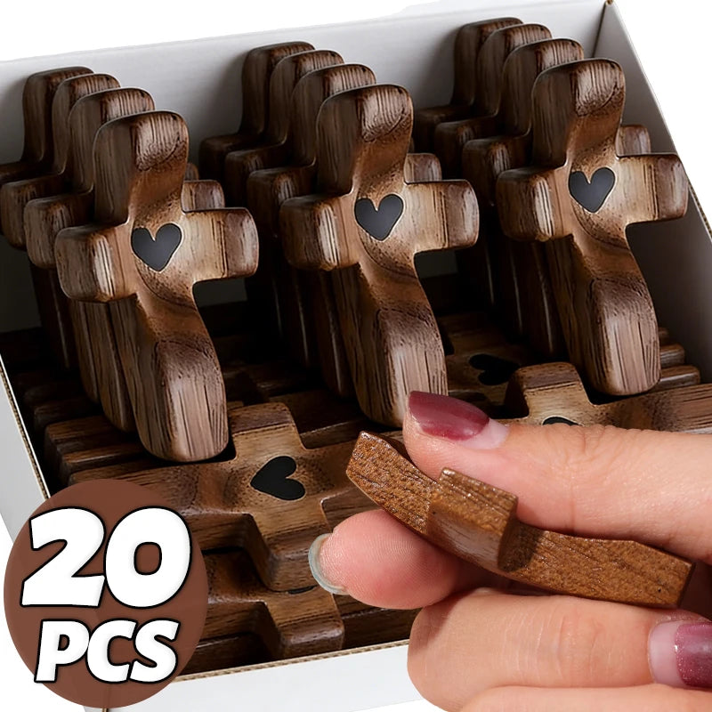 A hand holds a wooden pocket cross for prayer, showing multiple crosses in a box.