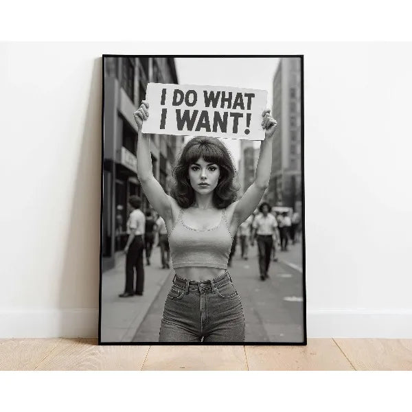 A black and white photograph of a woman holding a sign that reads I DO WHAT I WANT!
