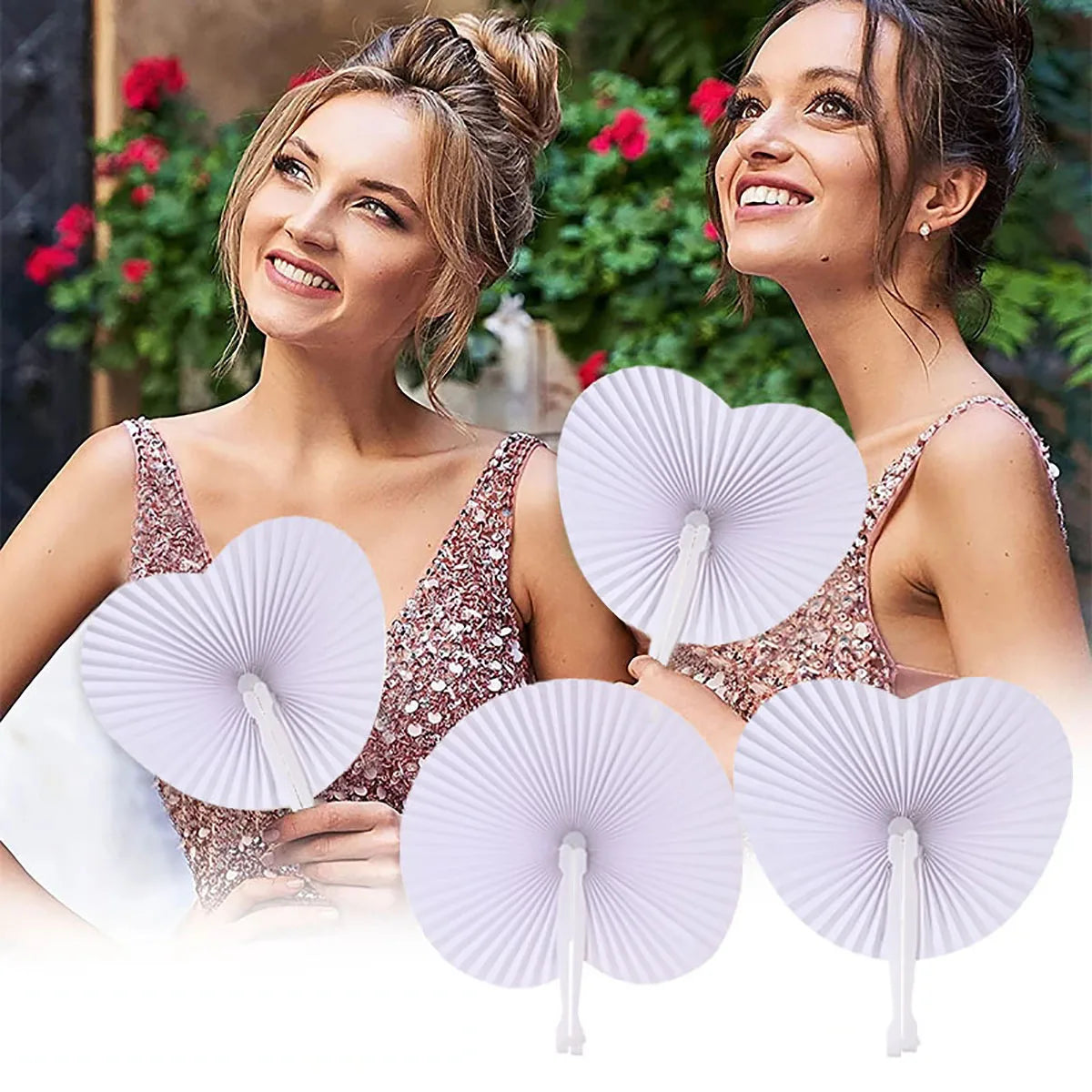 Two women smiling while holding heart-shaped white paper folding fans