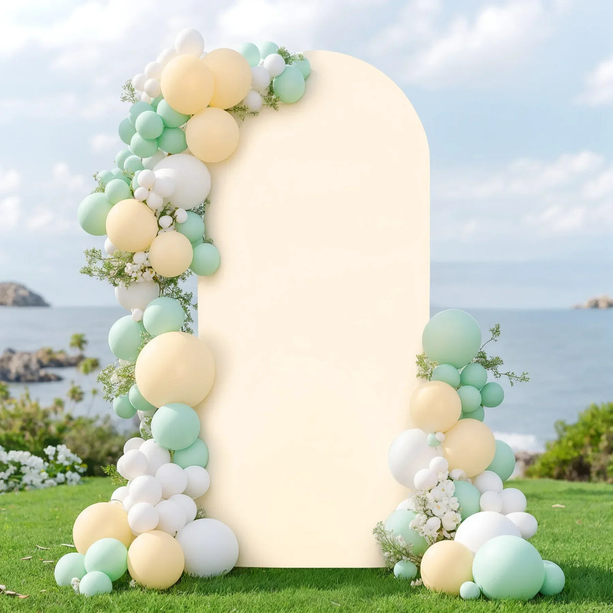 A double-sided arch backdrop cover decorated with round balloons in pale yellow and mint green tones on a grassy outdoor sett