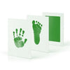 A set of white framed prints featuring green handprint and footprint imprints.