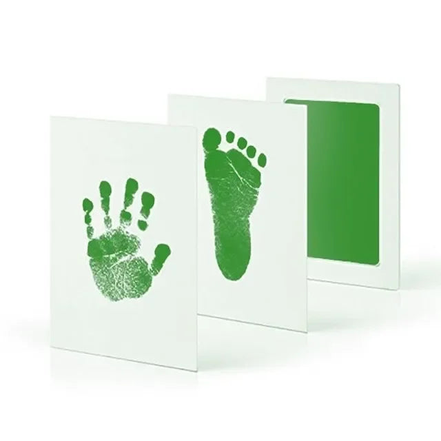 A set of white framed prints featuring green handprint and footprint imprints.