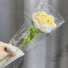 A handmade crochet tulip bouquet featuring yellow and white petals wrapped in clear cellophane.