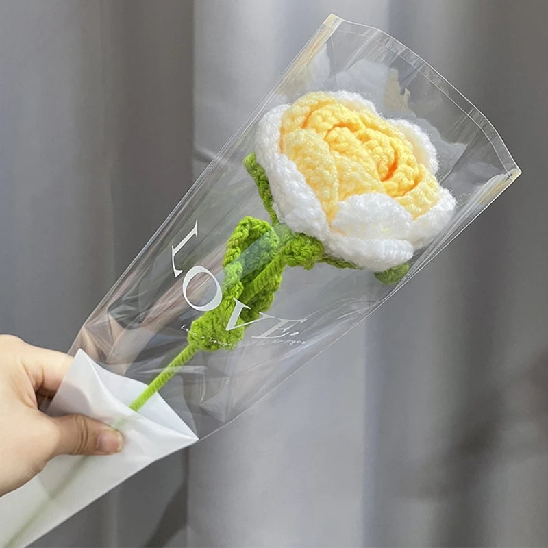 A handmade crochet tulip bouquet featuring yellow and white petals wrapped in clear cellophane.