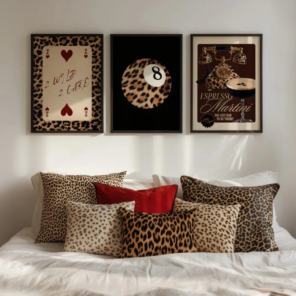 Un mur de galerie avec trois impressions encadrées à motif léopard et accents dorés au-dessus d'un lit.