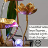 A golden iron flower fountain with colored lights that change color, featuring water flow and smooth stones.