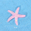 A pink starfish mermaid cake topper with glitter details is shown on a blue textured surface.