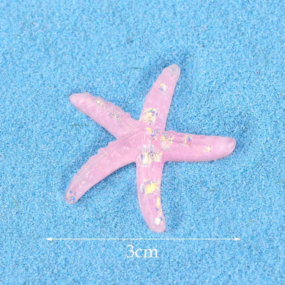 A pink starfish mermaid cake topper with glitter details is shown on a blue textured surface.