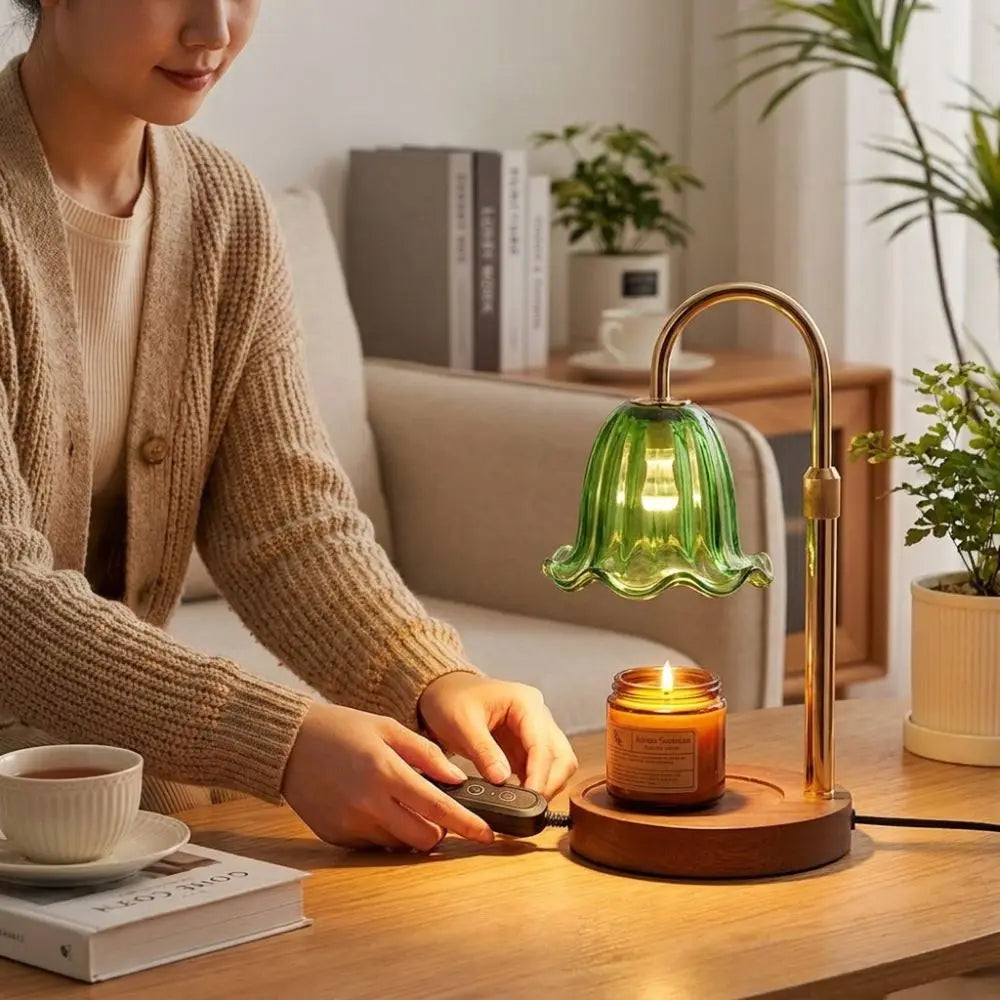 A person is using an adjustable height aromatherapy candle warmer lamp with a green glass shade on a wooden table.