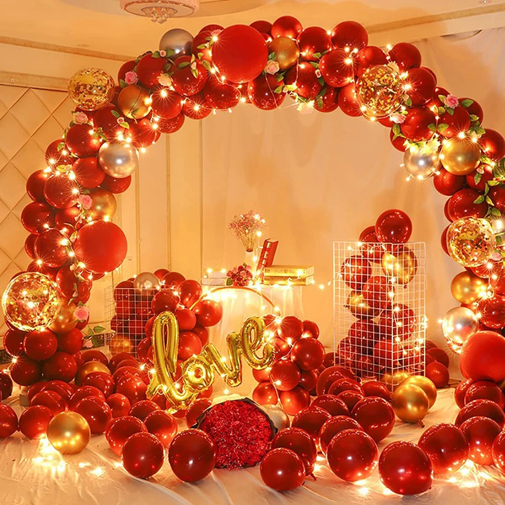 A vibrant red and gold balloon garland arch decorated for parties and celebrations.