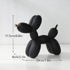 A black resin sculpture of a dog shaped like a balloon, displayed on a white surface.