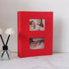 A red linen-cover photo album with two visible photo pockets showing a couple.