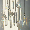 A set of seven crystal prism sun catchers hanging vertically, casting colorful light patterns on a white surface.