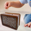 A hand is dropping a gold coin into a wooden piggy bank for saving goals.