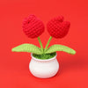 Hand woven red crochet flowers in green leaves potted in a white ceramic cup