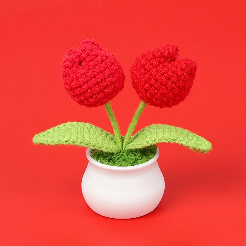 Hand woven red crochet flowers in green leaves potted in a white ceramic cup