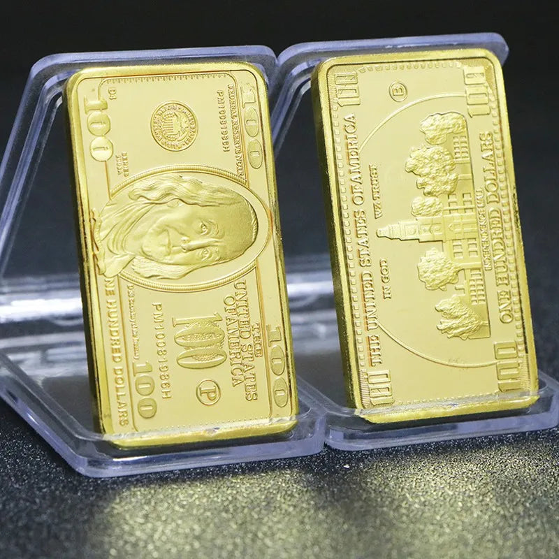 Two gold plated 100 dollar paper currency notes in protective plastic holders.