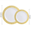 A set of two white plastic dinner and dessert plates with gold rims.