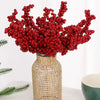 A vase filled with artificial red holly berry stems used for Christmas decor.