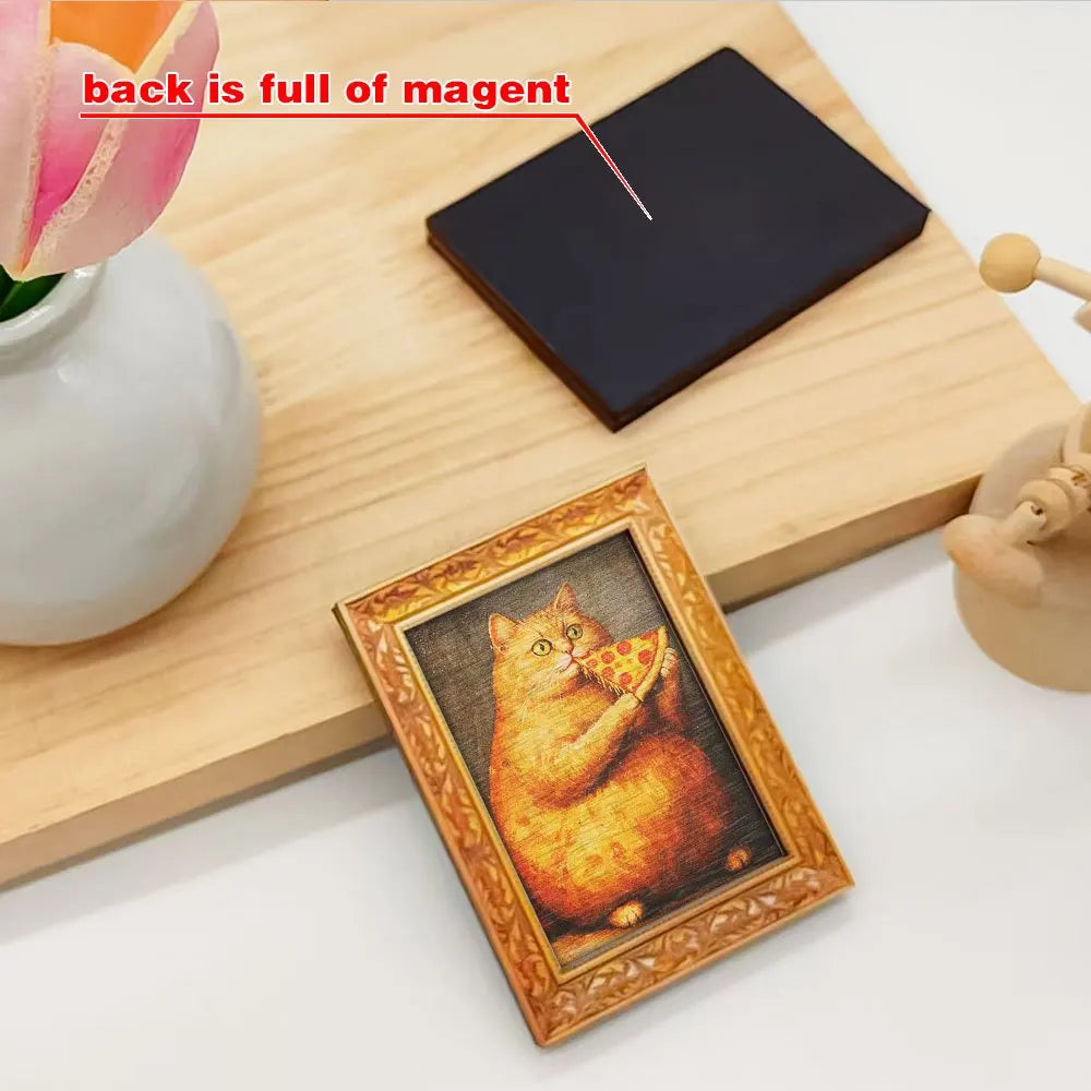 A wooden cutting board shows a gold-framed picture of an orange cat eating pizza and a black magnet with a pink flower.